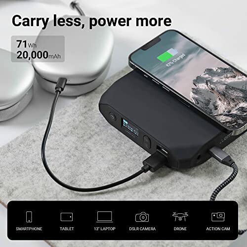 Power bank charging a smartphone with headphones nearby.